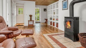 Una sala de estar acogedora con chimenea, sofás de cuero y techo de madera.