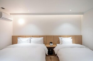 A hotel room with two beds, a wooden headboard, a bedside table with a phone, and an air conditioning unit. - Brown Dot Hotel NamGumi (Chilgok)