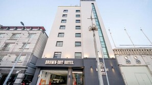 A multi-story hotel with a prominent 'BROWN-DOT HOTEL' sign, a modern facade, and a visible entrance with a car parked outside. - Brown Dot Hotel NamGumi (Chilgok)