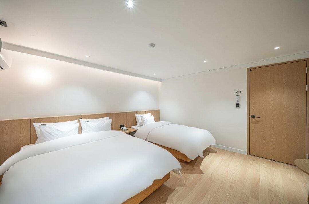 A hotel room with two beds, a wooden wardrobe, and a number 501 on the wall.