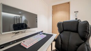 A modern office chair, a large flat-screen monitor, a keyboard, and a desk with a power strip. - Brown Dot Hotel NamGumi (Chilgok)