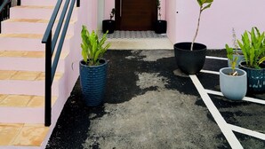 Un bâtiment rose avec un escalier menant à une porte, des plantes en pot et une petite fenêtre.
