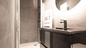 Une salle de bain moderne avec une douche, un lavabo et un miroir.