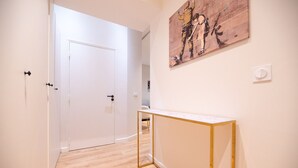 Un couloir avec une porte blanche, un plancher en bois et un tableau accroché au mur.