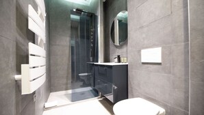 A modern bathroom with a glass shower enclosure, a white toilet, and a dark vanity.