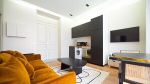 A modern living room with a sofa, a coffee table, and a kitchen area with appliances.