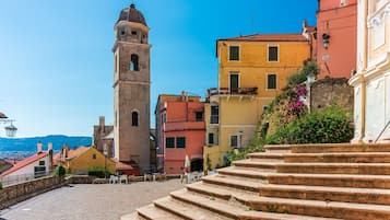 Una plaza histórica con calles empedradas, una imponente torre de campanas y edificios coloridos.