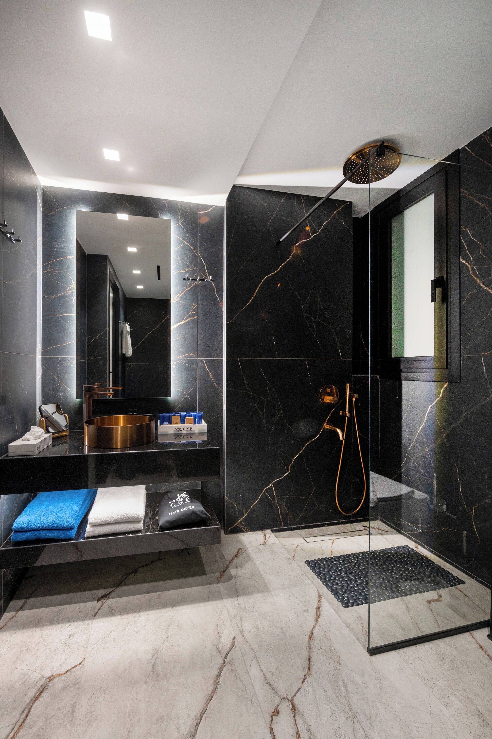 Une salle de bain moderne avec une douche à parois de verre, un meuble-lavabo avec un miroir et un sol carrelé en marbre.