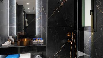 Une salle de bain moderne avec une douche à parois de verre, un meuble-lavabo avec un miroir et un sol carrelé en marbre.