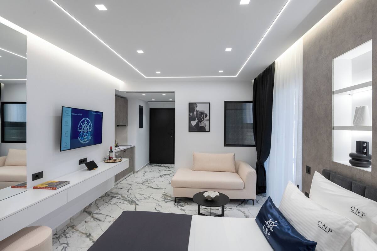 Une chambre d’hôtel moderne équipée d’un grand lit, d’un canapé, d’une télévision, d’un bureau et d’une salle de bain.