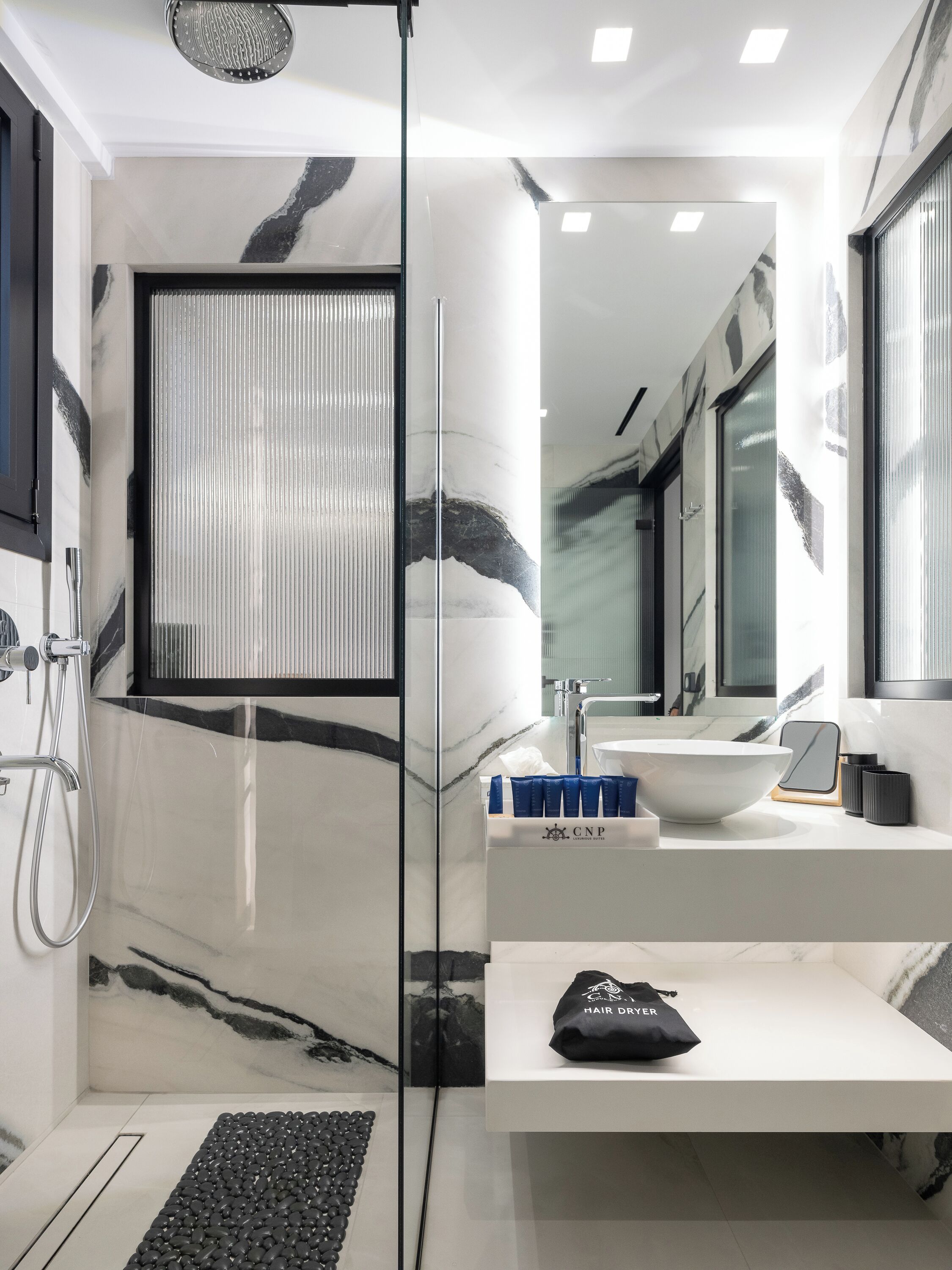 A modern bathroom with a glass shower enclosure, a white sink, and a large mirror.