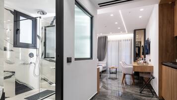 A modern bathroom with a glass shower enclosure, a vanity with a mirror, and a seating area with a sofa and chairs.