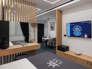 A modern hotel room with a bed, a desk, a chair, a TV, and a wardrobe.