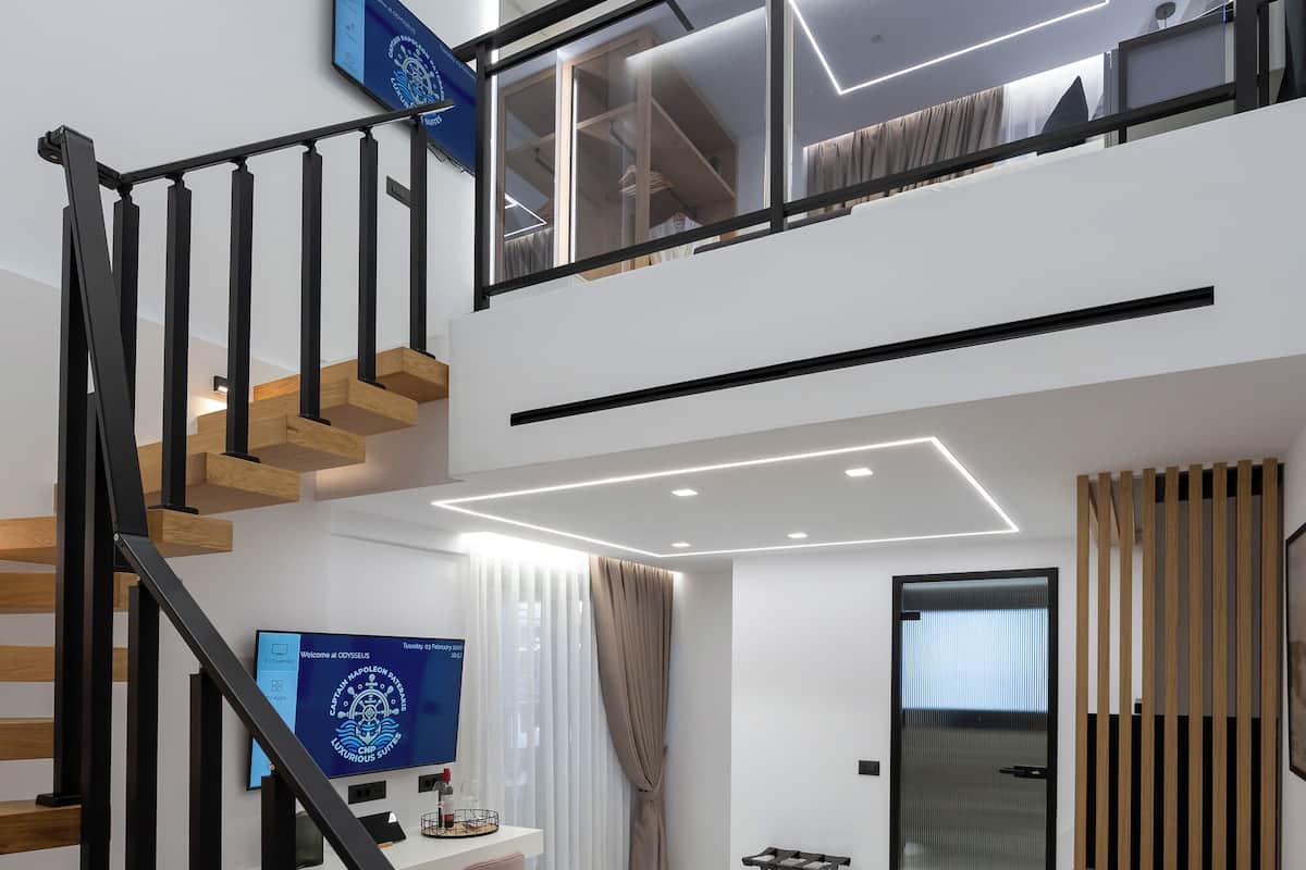Un salon moderne avec un escalier, un téléviseur à écran plat, un canapé et une table basse.