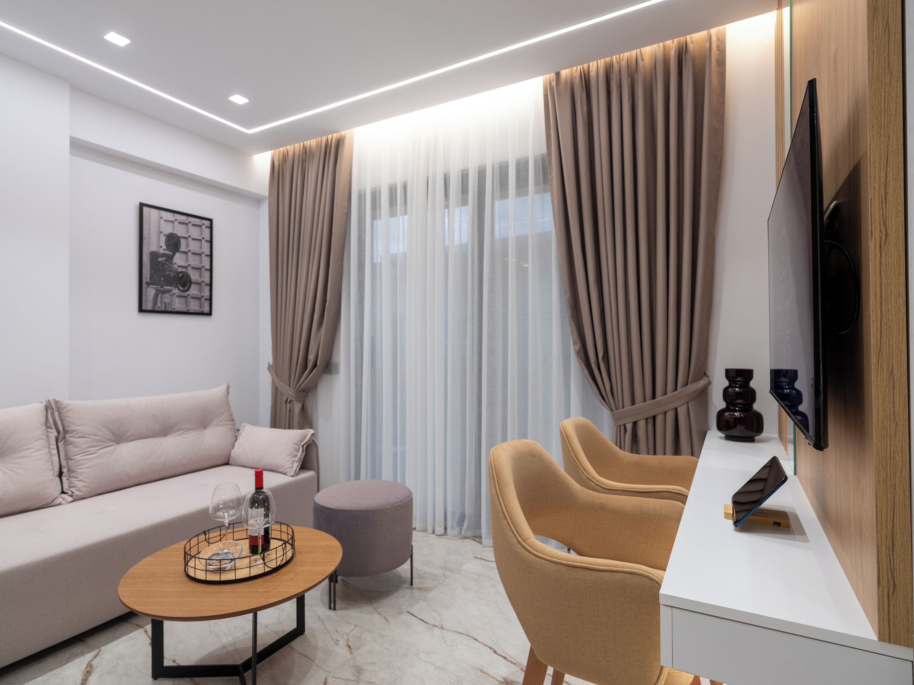 A modern living room with a sofa, a round coffee table, a side table, and a TV mounted on the wall.