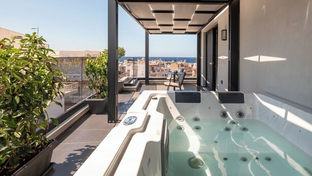 Terraza en la azotea con jacuzzi, zona de estar y plantas en macetas.