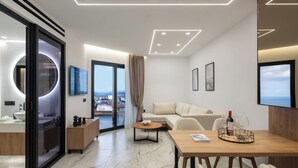 Una habitación de hotel moderna con balcón, un espejo redondo, un sofá, una mesa de comedor y un televisor.