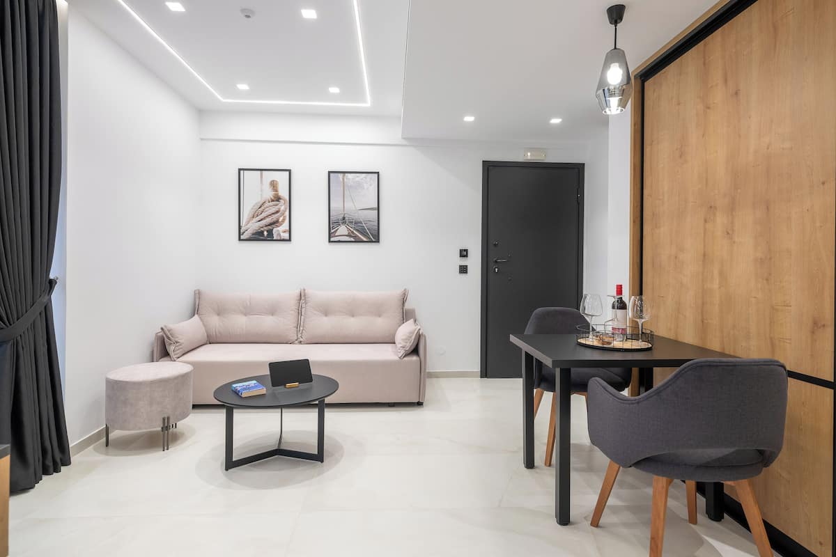 Un salon moderne comprenant un canapé, une table basse ronde, une table à manger avec des chaises et deux tableaux encadrés accrochés au mur.