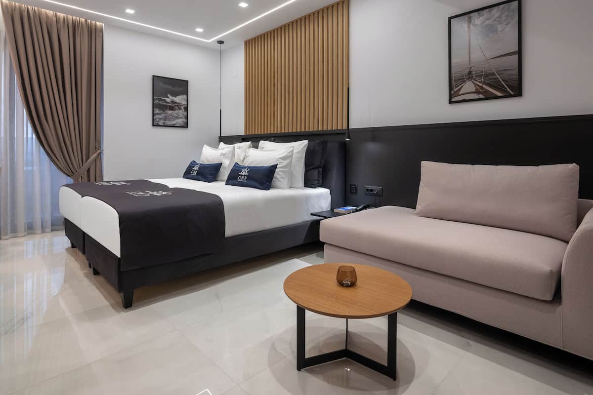 Une chambre d’hôtel moderne avec un lit, un canapé, une petite table et un tableau au mur.