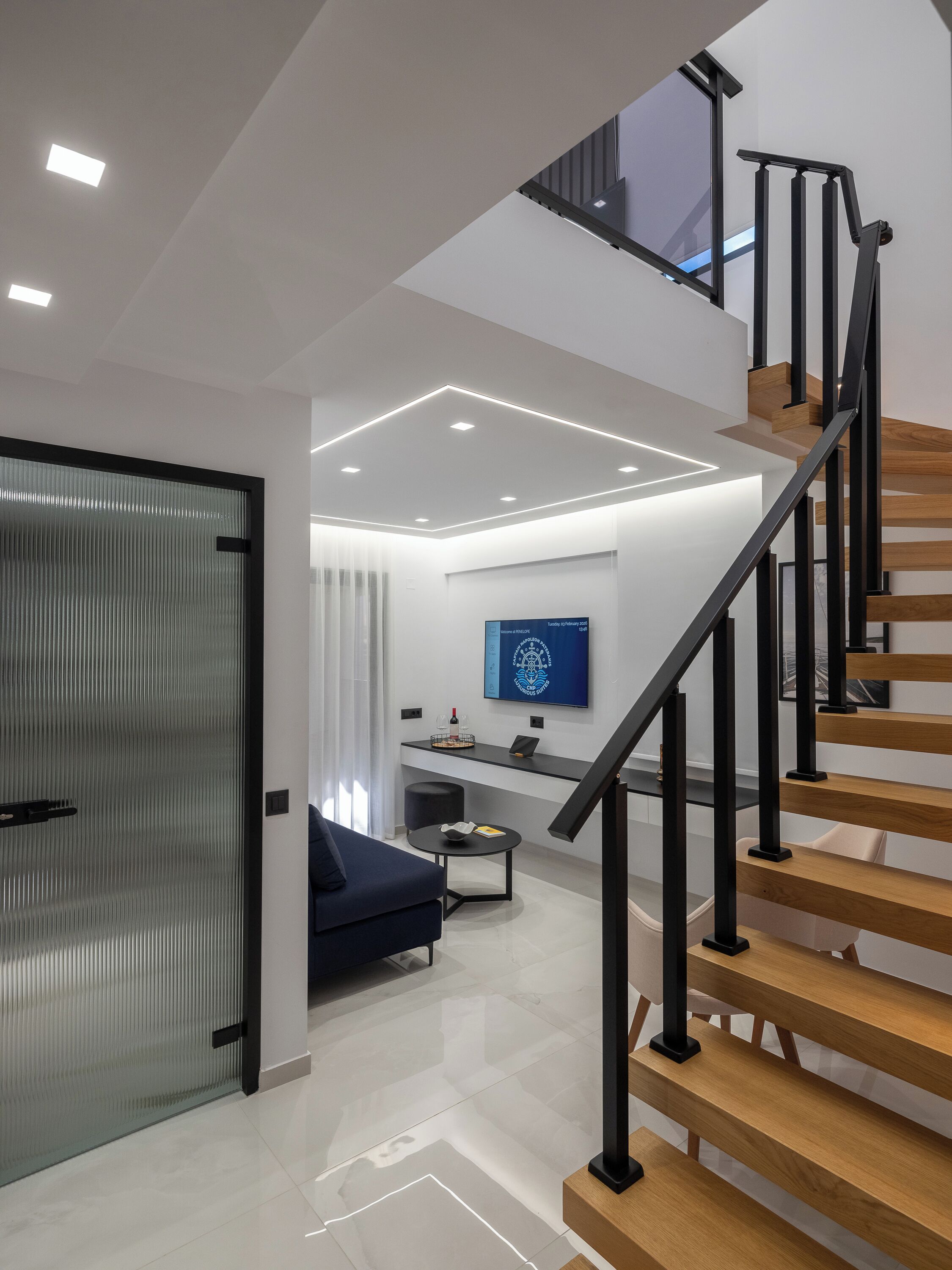 A modern interior with a staircase, a living area, and a wall-mounted television.