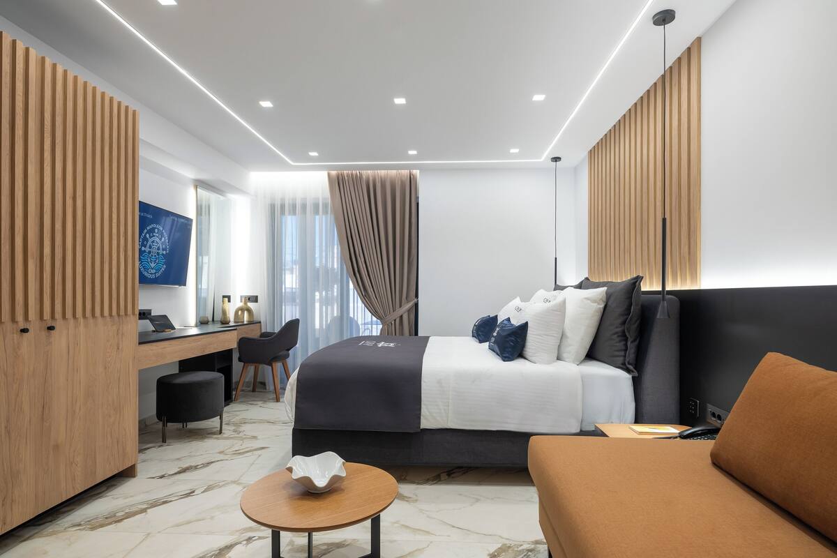 Une chambre d’hôtel moderne équipée d’un lit, d’un bureau, d’une chaise, d’une table ronde et d’un téléviseur.