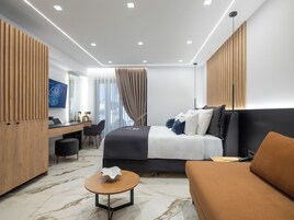 A modern hotel room with a bed, a desk, a chair, a round table, and a television.