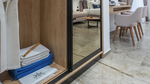Una habitación de hotel moderna con un armario de madera, una zona de comedor con mesa y sillas, y un espejo grande que refleja la habitación.