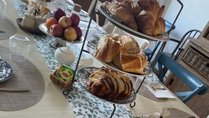 A breakfast table set with croissants, bread, apples, and a teapot. - Le Clos du Bas Courtil (Osmanville)