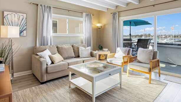 Ein Wohnzimmer mit einer Couch, Sesseln, einem Couchtisch und Blick auf eine Marina durch große Fenster.