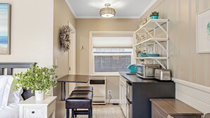 Una cocina compacta con horno empotrado, un pequeño comedor con banco y una ventana con persianas.