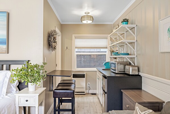 A compact kitchen with a built-in oven, a small dining area with a bench, and a window with blinds.