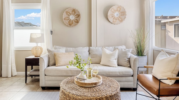 A living room with a beige sofa, a coffee table with decorative items, a lamp, and two wall art pieces.