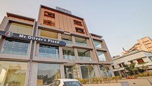 Un immeuble à plusieurs étages abritant un restaurant Mc Oliver's Pizza au rez-de-chaussée.