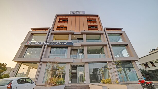 Un immeuble à plusieurs étages avec une enseigne indiquant « Mc Oliver’s Pizza ».