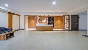 Un hall d’entrée spacieux avec un comptoir de réception, des lambris en bois et un canapé bleu.