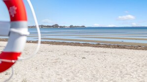A lifebuoy on a sandy beach with calm water and a clear sky. - "Cornelius" - 30m from the sea by Interhome (Bjert)