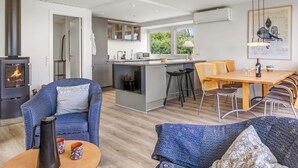 A modern living room with a fireplace, a dining area with a wooden table, and a kitchen with a central island. - "Cornelius" - 30m from the sea by Interhome (Bjert)