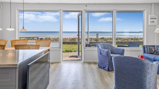 A modern kitchen with a large island, wooden chairs, and a view of the beach through large windows. - "Cornelius" - 30m from the sea by Interhome (Bjert)