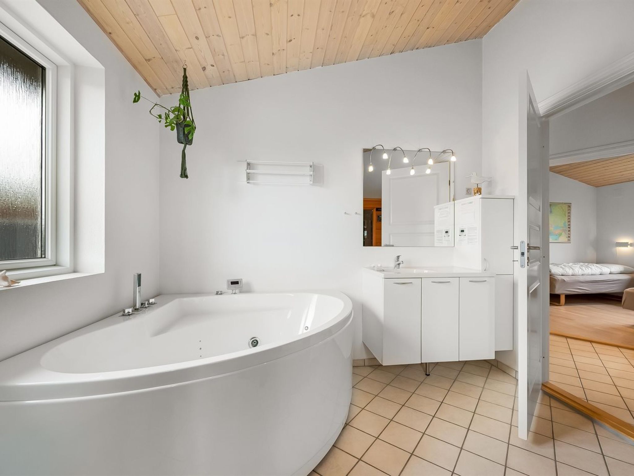 A modern bathroom with a freestanding bathtub, a vanity with a mirror, and a window.