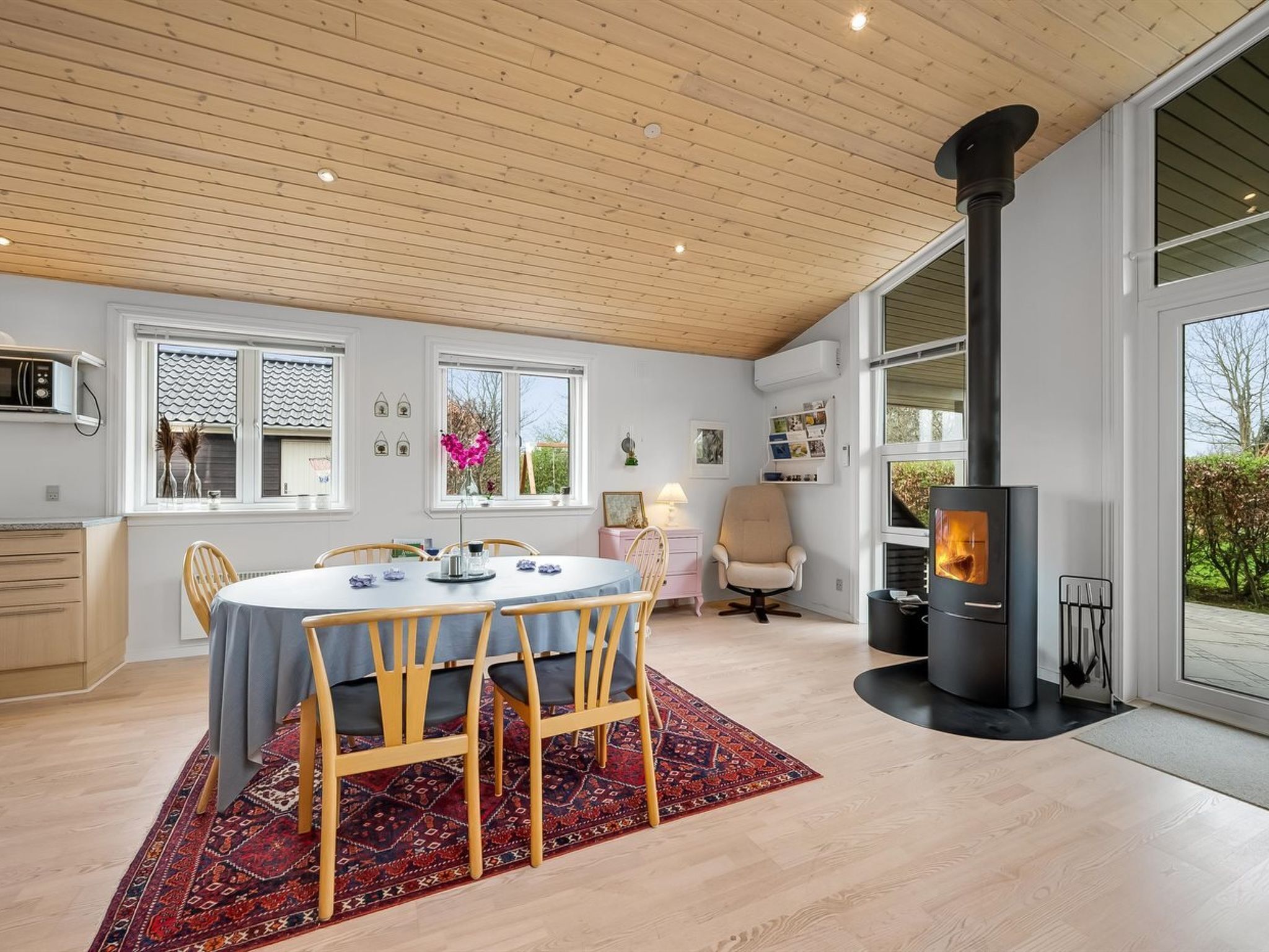 Une cuisine moderne dotée d’une grande cuisinière, d’un plafond en bois et d’un coin repas avec une table ronde et des chaises.