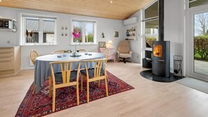 A modern kitchen with a large stove, wooden ceiling, and a dining area with a round table and chairs. - "Gertrud" - 950m to the fjord by Interhome (Tarm)