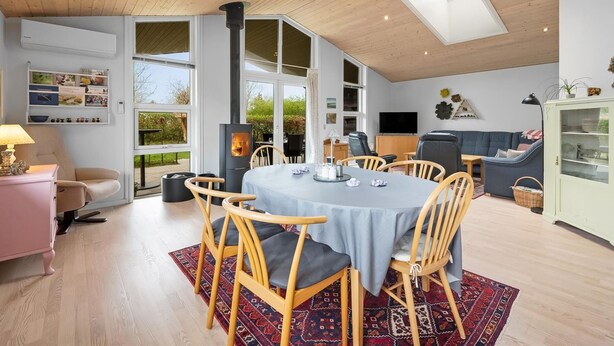 A spacious living area with a high ceiling, a large dining table, and a built-in fireplace. - "Gertrud" - 950m to the fjord by Interhome (Tarm)