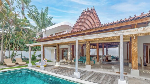 A poolside area with a covered patio, lounge chairs, and a small inflatable unicorn float. - Central Canggu Walk to Nelayan Beach - 3BR Villa (kuta utara)