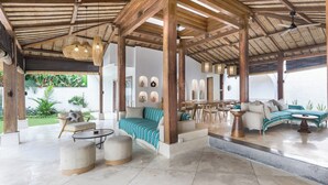 A spacious outdoor lounge area with a wooden pergola, comfortable seating, and a view of the ocean. - Central Canggu Walk to Nelayan Beach - 3BR Villa (kuta utara)