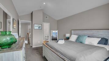 A bedroom with a large bed, a dresser, and a green vase.