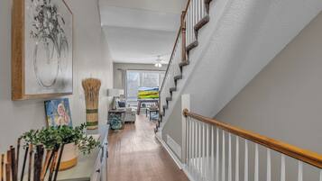 A staircase with white railings and a wooden handrail, leading to a room with a view of the outdoors.