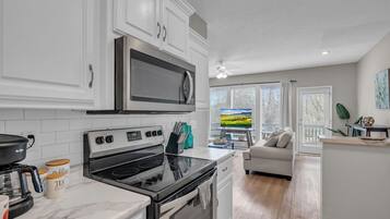A modern kitchen with white cabinetry, a stainless steel refrigerator, and a black stove.