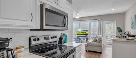Una cocina moderna con armarios blancos, un refrigerador de acero inoxidable y una estufa negra.