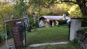 Ein rustikales Haus mit einer Metallbedachung, umgeben von Bäumen und einem grünen Rasen.