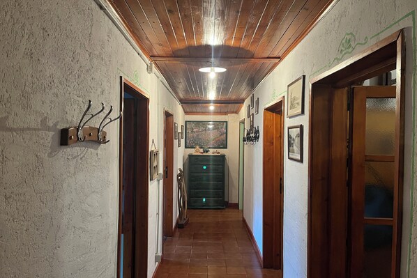 Un couloir avec un plafond et des murs en bois, une armoire verte et des tableaux encadrés.